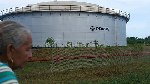 A woman walks near of a oil storage tank of Venezuela's state-run oil company, PDVSA in Cabimas, Venezuela