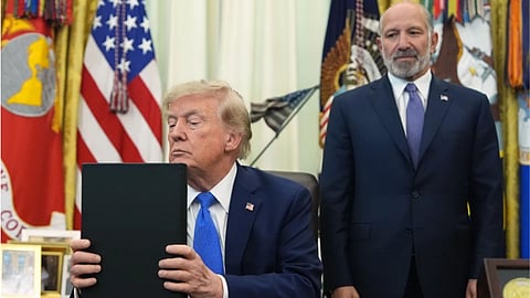 President Donald Trump listens before signing executive orders in the Oval Office of the White House, in Washington, as Commerce Secretary Howard Lutnick watches.