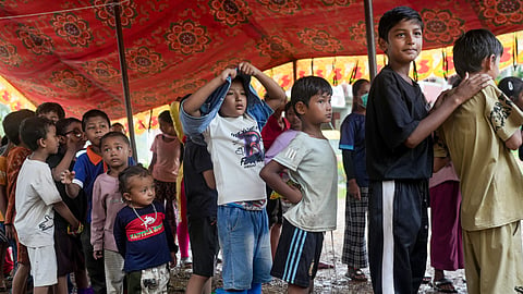 Children displaced by recent flash floods and mudslides queue under a makeshift tent to receive food and relief distribution in Nuwakot district, Nepal