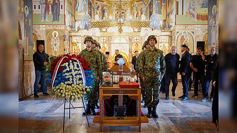 A man touches the cross as Serbian national military servicemen stand around the coffin of the former Bosnian Serb army commander Ratko Mladic, who died last week while serving a life sentence for genocide and other atrocities during the war in Bosnia, at the St. Luka Church, in Belgrade, Serbia.