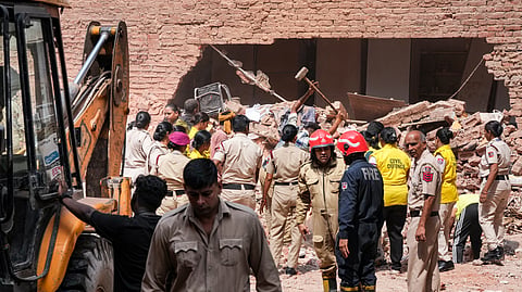 Police personnel, Delhi Fire Service officials, and Civil Defence volunteers coordinate debris clearing efforts following the collapse of a multi-storey building housing a PG, at Satya Niketan, in New Delhi