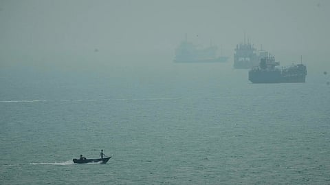 A motorboat travels past commercial vessels anchored amid haze in the Strait of Hormuz off Bandar Abbas, Iran, Monday, Sept. 7, 2026.