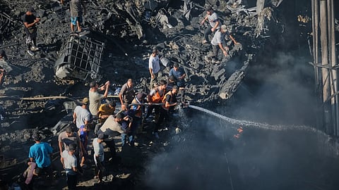 Palestinians try to extinguish a fire in the rubble of a destroyed building following an Israeli airstrike in Gaza City