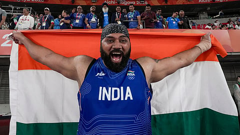 India's Tajinderpal Singh Toor holds a National Flag as he celebrates after winning a silver medal in the men's shot put final event during the 20th Asian Games