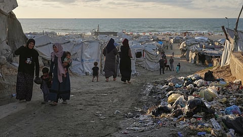 Women walk along a street surrounded by tents sheltering displaced Palestinians, in Gaza City