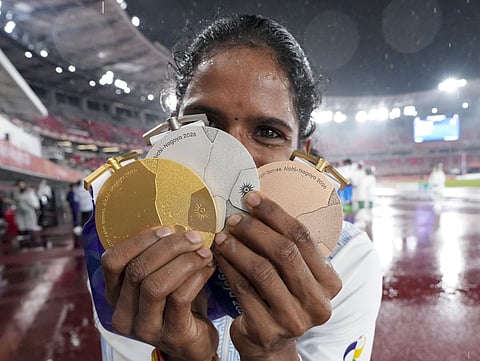 Vithya Ramraj poses for photographs with gold, silver and bronze medals she won in the ongoing Asian Games 2026
