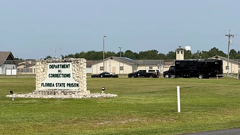 Law enforcement vehicles sit parked outside the Florida state prison in Starke, Fla