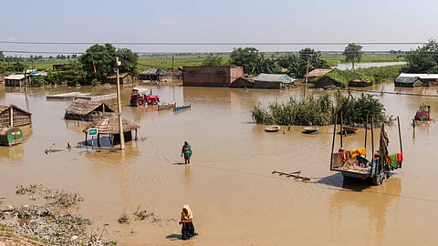 People wade through a partially inundated area, at Khairatwa village in West Champaran