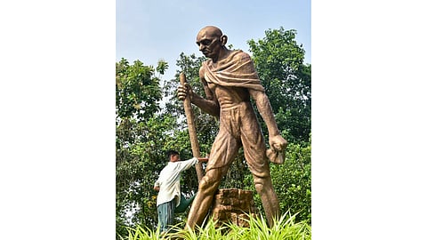 A worker cleans a statue of Mahatma Gandhi ahead of Gandhi Jayanti