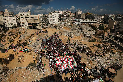 Mourners gather around the flag-draped remains of Palestinians killed in Israeli strikes during the war with Hamas
