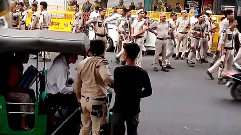 A policeman tries to evict a person in Connaught Place as heavy police deployment and entry restrictions are enforced ahead of a planned protest by Cockroach Janta Party (CJP) members, in New Delhi.