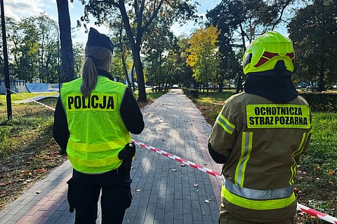 A police officer and a volunteer firefighter look down the street near a cordoned-off area following an attack on the Vocational School Complex No. 4 in Ostroleka, Poland, Wednesday, Oct. 7, 2026.