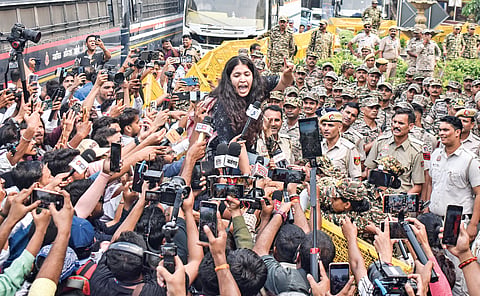 A demonstrator addresses the media as security personnel watch, at Connaught Place on Saturday