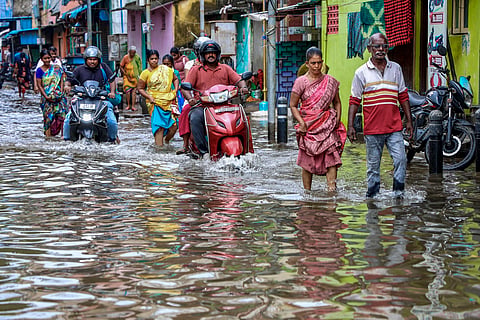 Chennai: Commuters wade through a waterlogged street following heavy rain, in Chennai, Sunday, Oct. 18, 2026. 