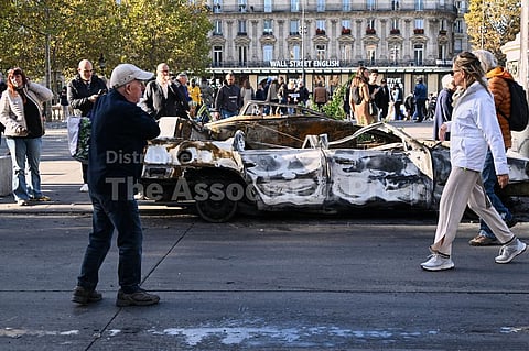 People look at a charred car on Place de la Republique the day after a demonstration against rising living costs, joining students' grievances, in Paris, Sunday, Oct. 18, 2026.