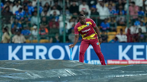 West Indies' Rovman Powell inspects the covered pitch during a rain interruption in the fifth and final T20I cricket match of the series between India and West Indies, in Bengaluru, Saturday, Oct. 17, 2026