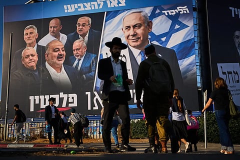 People walk past a Likud party campaign billboard featuring Israeli Prime Minister Benjamin Netanyahu alongside opposition party leaders and bearing the Hebrew slogan "Right or Palestine," ahead of Israel's general election, in Beni Brak, Israel, Sunday, Oct. 18, 2026. 