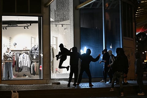  Youths break a store window during clashes between protestors and police in Paris, Sunday, Oct. 18, 2026.