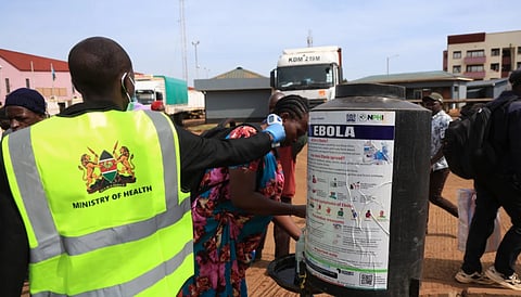 People disinfect their hands as a Kenyan health worker checks the temperatures of travelers crossing from Uganda to Kenya as part of measures to contain the spread of Ebola virus, in Busia, Kenya