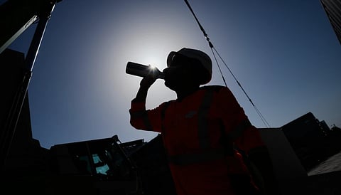 A worker drinks water on a construction site during high temperatures in Boulogne Billancourt