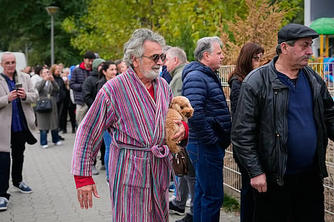 A man holds a dog while arriving at a polling station to vote in a parliamentary election in Belgrade, Serbia