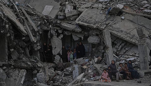 Palestinian women and children watch the Palestine Strongman Championship from among the rubble of destroyed buildings in Gaza City