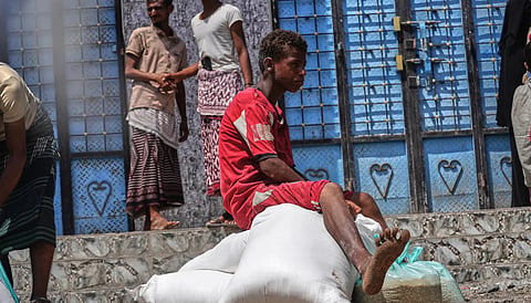 A displaced Yemeni boy sits on sacks of food aid in the Salah al-Din area on the outskirts of Aden, Yemen