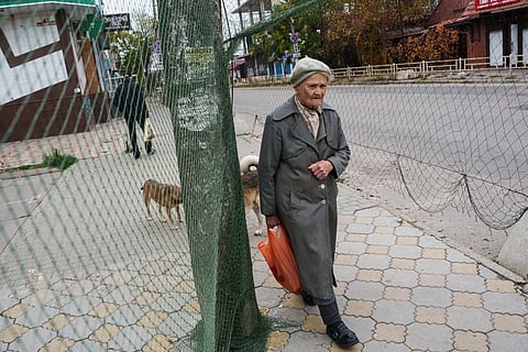 An elderly woman walks beneath anti-drone nets stretched over a street during a local ceasefire related to evacuation efforts in Oleshky, in Kherson, Ukraine, Tuesday, Oct. 27, 2026.