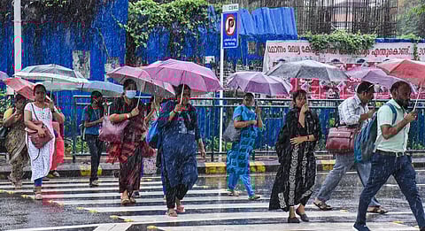 Pedestrians during monsoon rain in Kochi on Tuesday