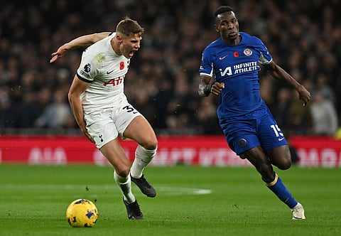 Tottenham Hotspur’s defender Micky van de Ven holds his leg as he reacts in pain while chasing Chelsea’s striker Nicolas Jackson