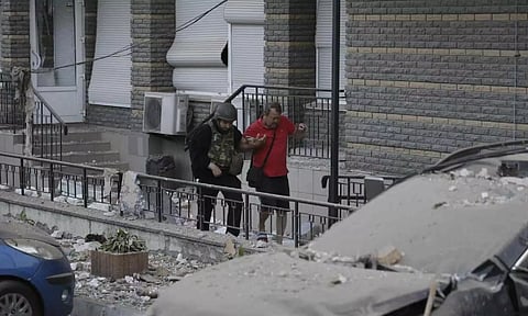 A police officer helps an injured man evacuate to an ambulance from a multi-story apartment building