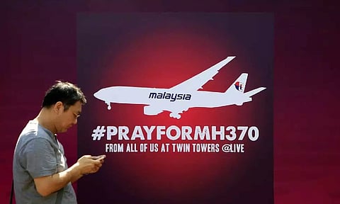 Man walks past a board reading "Pray for MH370" for passengers aboard a missing Malaysia Airlines plane, in Kuala Lumpur, Malaysia, on March 15, 2014. (AP)