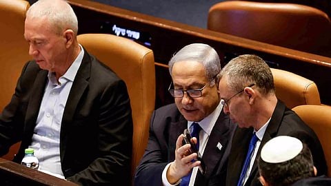 Israeli Prime Minister Benjamin Netanyahu shows Justice Minister Yariv Levin his phone as lawmakers gather at the Knesset plenum to vote on a bill that would limit some Supreme Court power, in Jerusalem