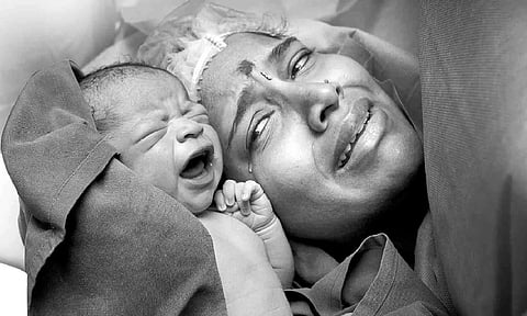 The first moment of a woman seeing her newborn as captured by Xciba