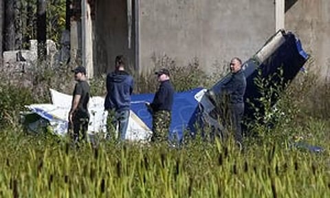 Russian servicemen inspect a part of a crashed private jet near the village of Kuzhenkino, Tver region (AP)