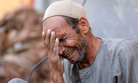 Man weeps after burying son. Reuters