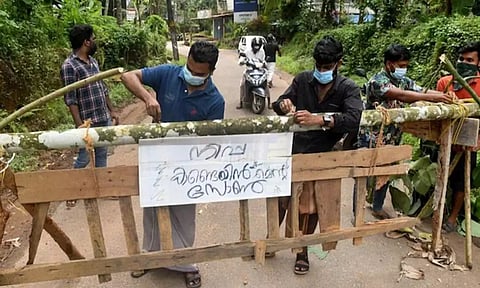 Residents fix a sign reading "Nipah containment zone" on a barricade in Kozhikode on September 13. (Reuters)