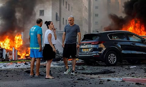 People react near a fire after rockets were launched from the Gaza Strip