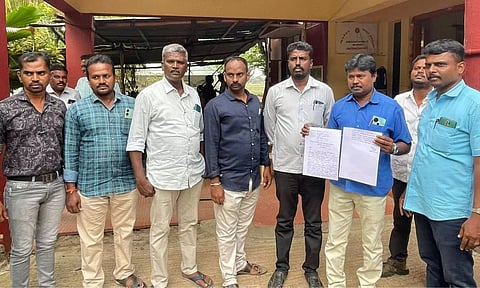 VAO M Karuppasamy with revenue officials after lodging a plaint against lorry driver at Ayakudi police station in Palani on Friday