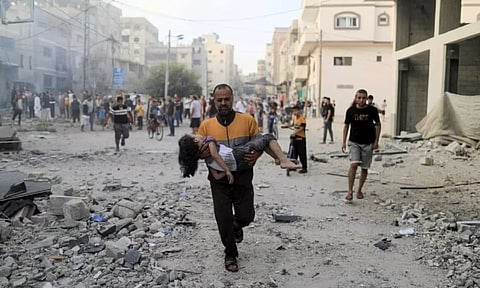 A Palestinian man carries a wounded girl at the site of Israeli strikes