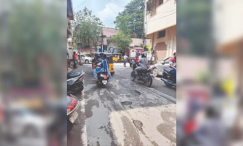 Commuters in vehicles struggle to navigate a potholed road in Choolai.
