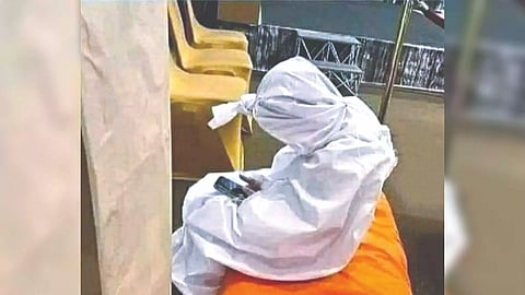 An image of a person sitting with a white sheet wrapped around their body