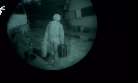 An Israeli army soldier walks towards a building structure carrying gallon containers (Image: REUTERS)