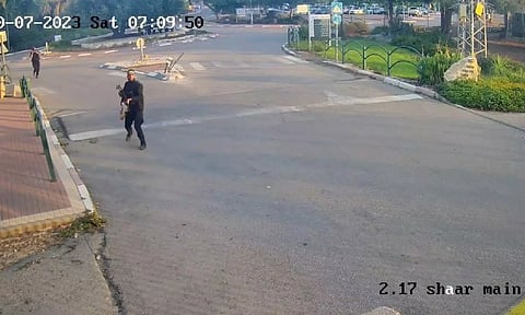 ] Armed men run holding guns during the October 7 attack by Hamas, in this screen grab from footage captured by a surveillance camera in Kibbutz Alumim, Israel