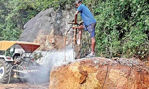 A worker trying to remove a huge boulder that fell on a road in the Nilgiris on Friday