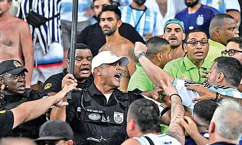 Brazilian police officers armed with batons try to regulate order amongst Argentine supporters