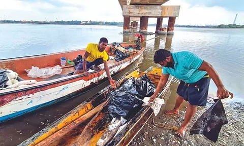Fishermen cleaning the oil-covered boats (Photo credit: Hemanathan M)
