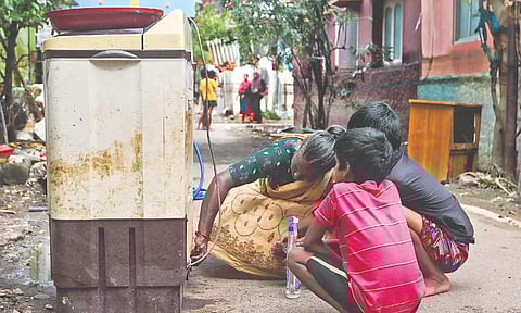 A mother and 2 kids scrubbing the oil from a washing machine.