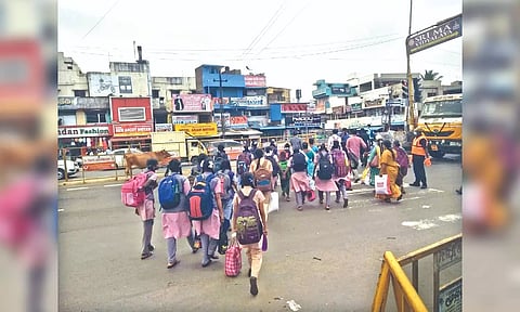 School children pass through the blocked pedestrian crossing in Guduvanchery.