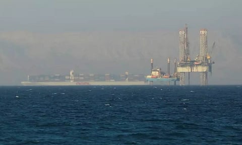 A container ship crosses an oil platform at the Gulf of Suez towards the Red Sea before entering the Suez Canal, outside of Cairo (Reuters)